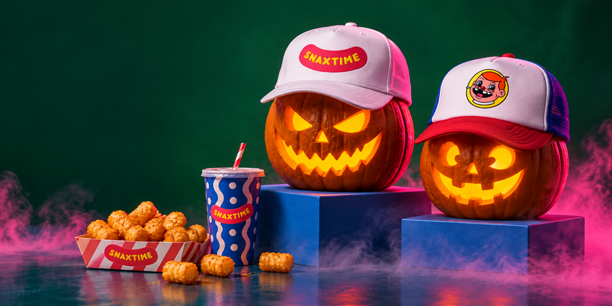 Glowing jack-o'-lanterns wearing Snaxtime hats beside golden tots in a striped food tray and a soda cup.