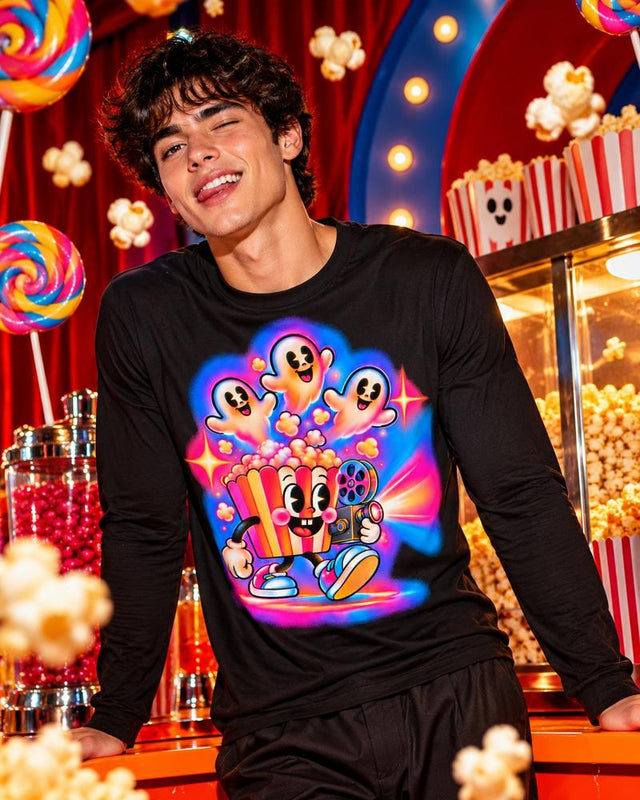 Model wearing the black Movietime Popcorn Ghosts long sleeve tee at a colorful cinema concession counter.