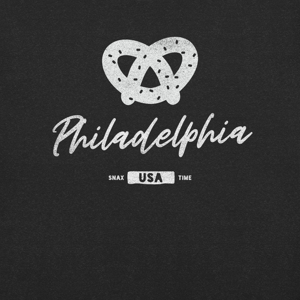 Close-up of a white salted pretzel and script "Philadelphia" printed on black heather fabric