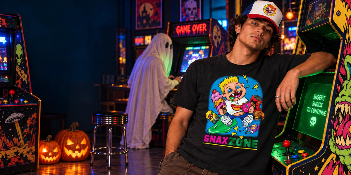 Model wearing the Snax Zone graphic tee and Snaxy trucker hat in a Halloween arcade