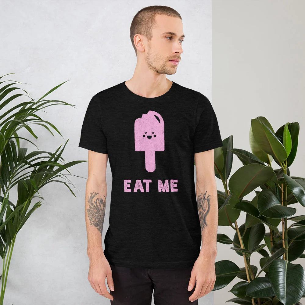 Man in the black heather Eat Me popsicle tee standing between houseplants
