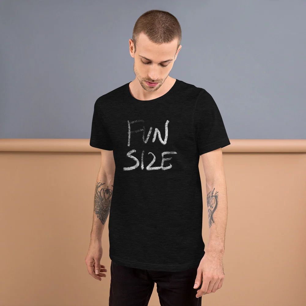 Person wearing a black heather FUN SIZE chalk-lettered t-shirt against a blue and tan wall